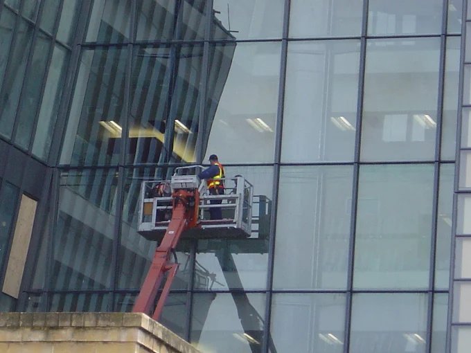 Window cleaner on a cherry picker cleaning a glass building facade